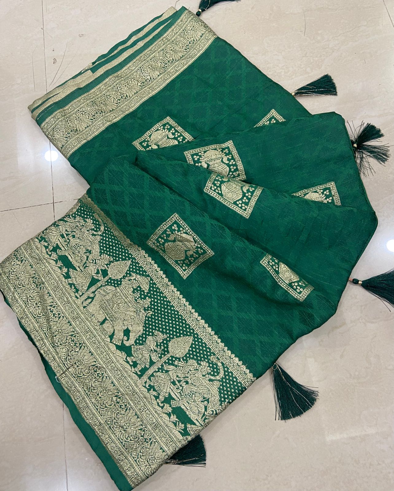 Green saree with intricate white patterns on a light gray floor