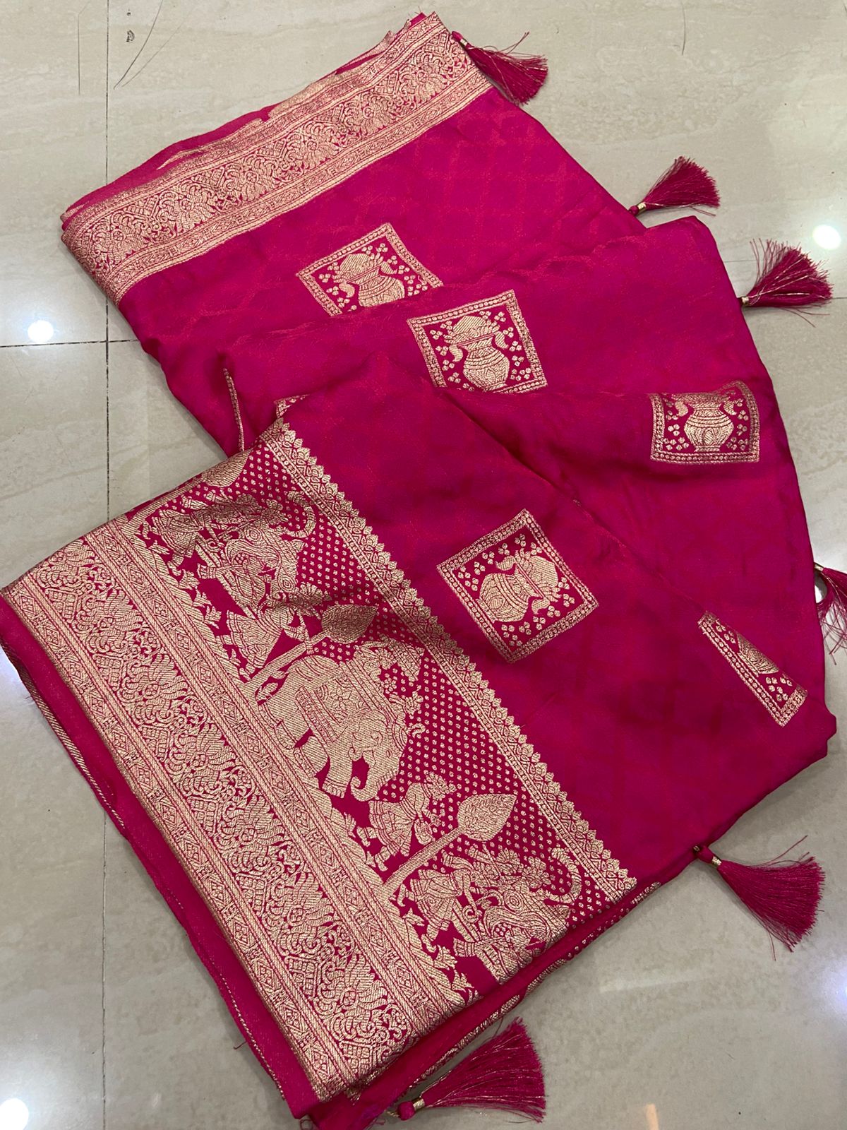Pink saree with intricate gold patterns on a tiled floor