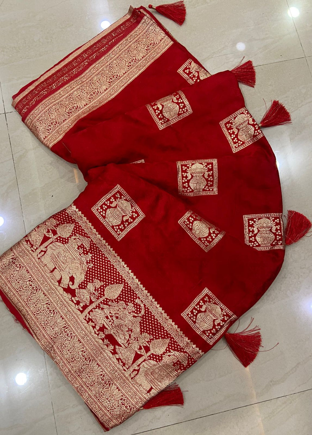 Red saree with gold patterns on a tiled floor