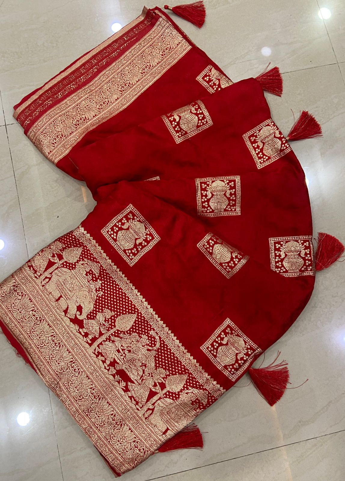 Red saree with gold patterns on a tiled floor