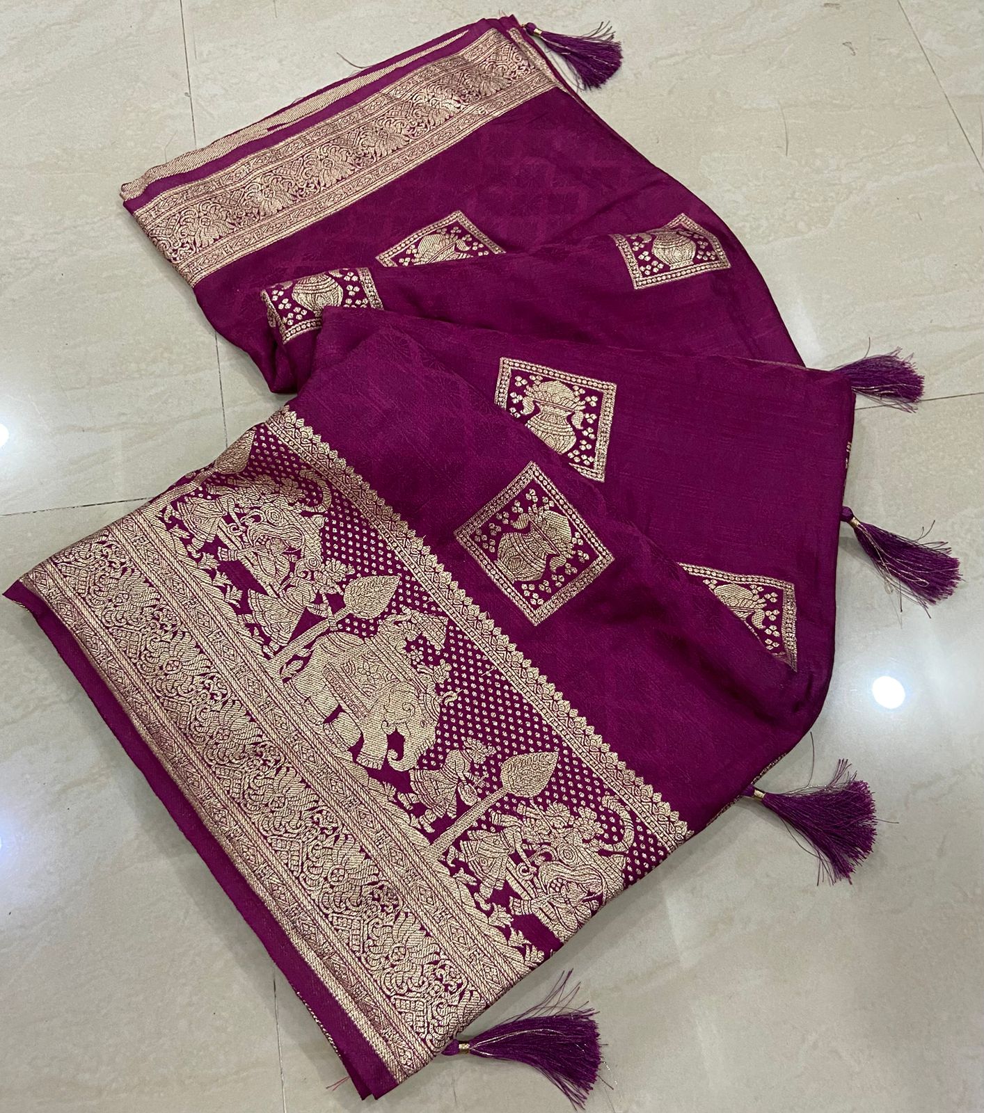 Purple fabric with intricate gold patterns and tassels on a light beige floor.
