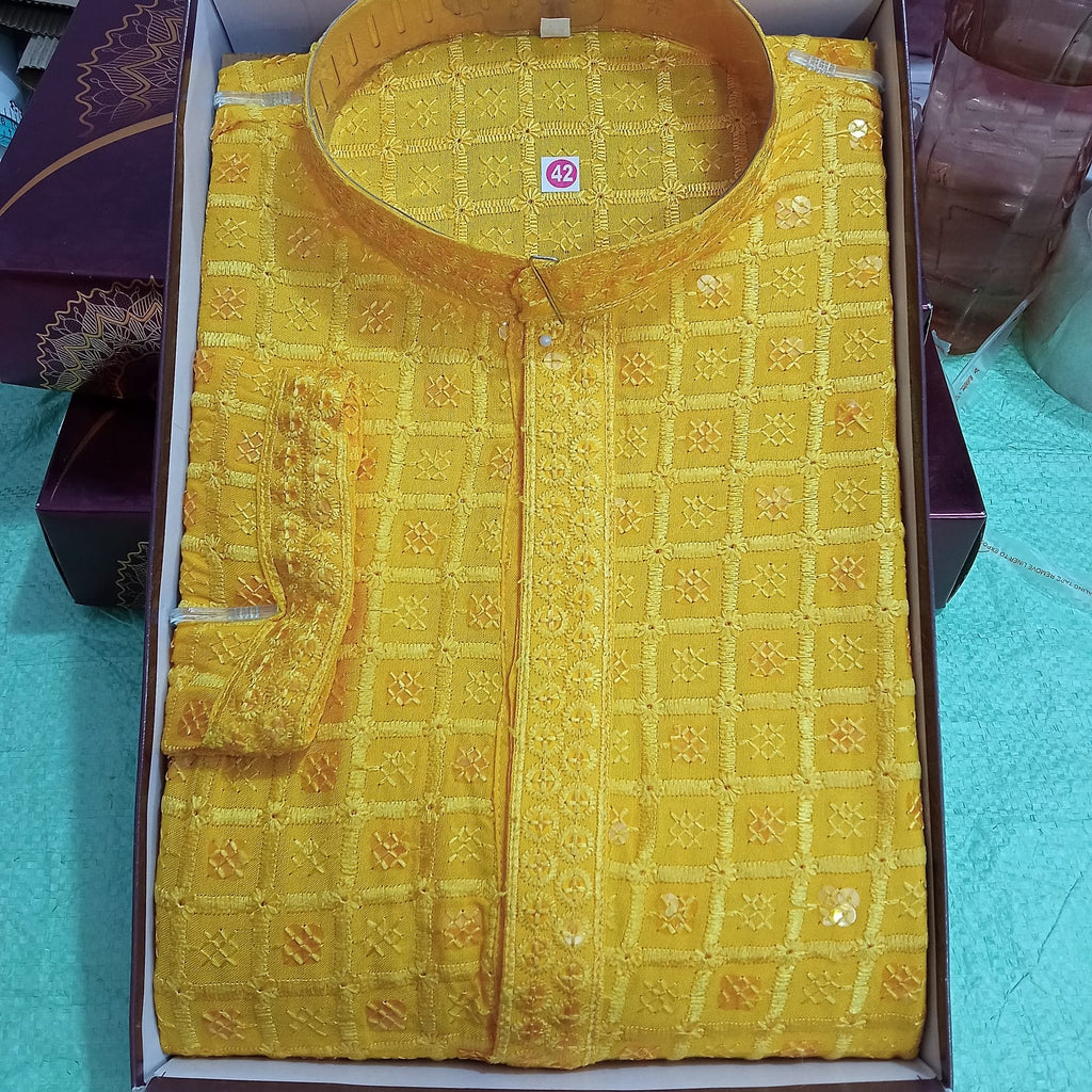 Yellow embroidered shirt in a box on a blue surface
