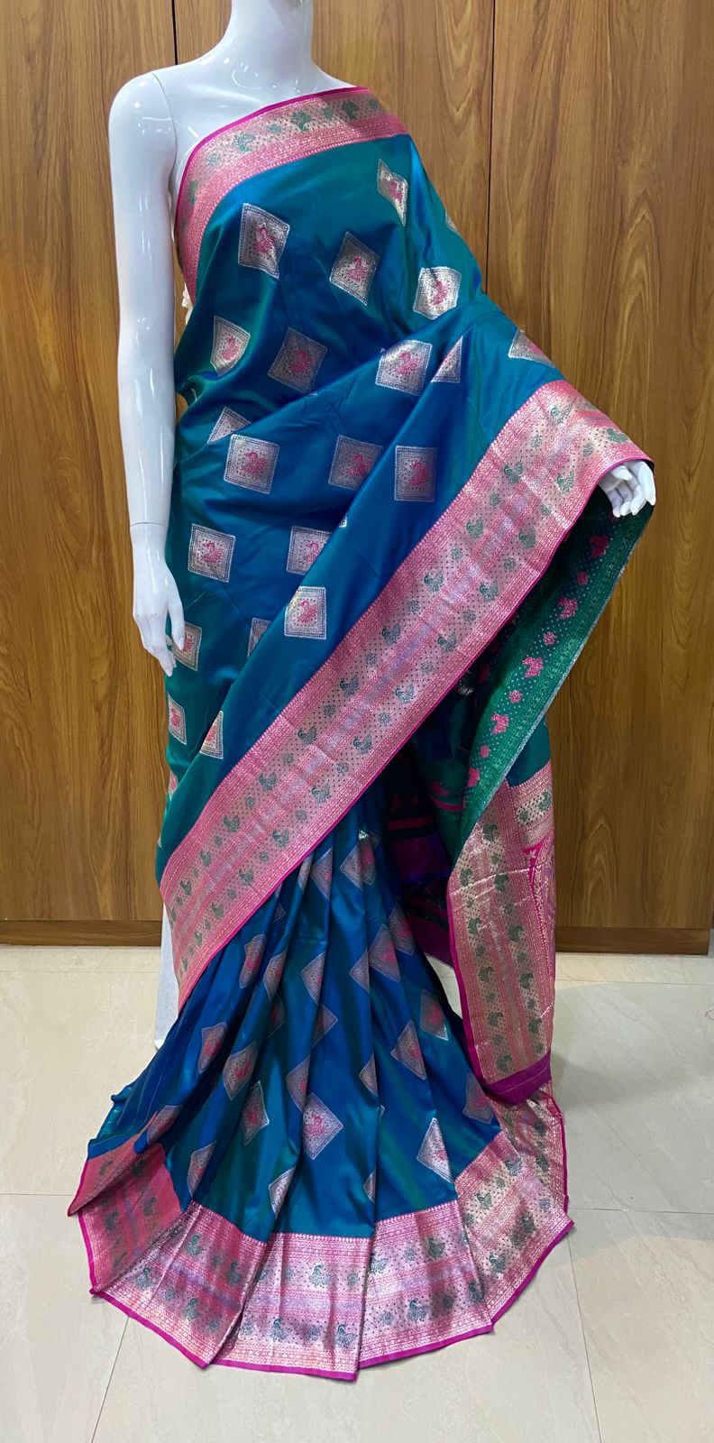 Saree with blue and green pattern displayed on a mannequin against a wooden background