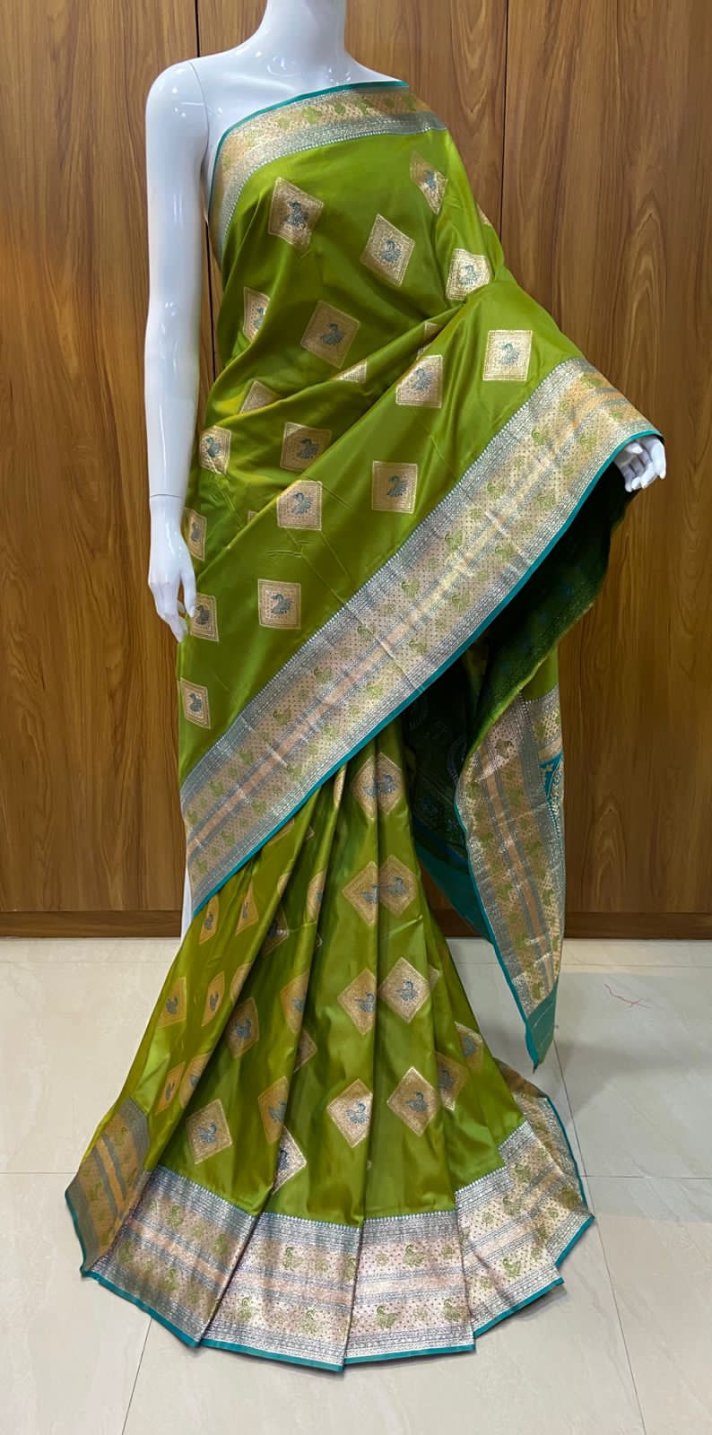 Green saree with gold patterns on a wooden background