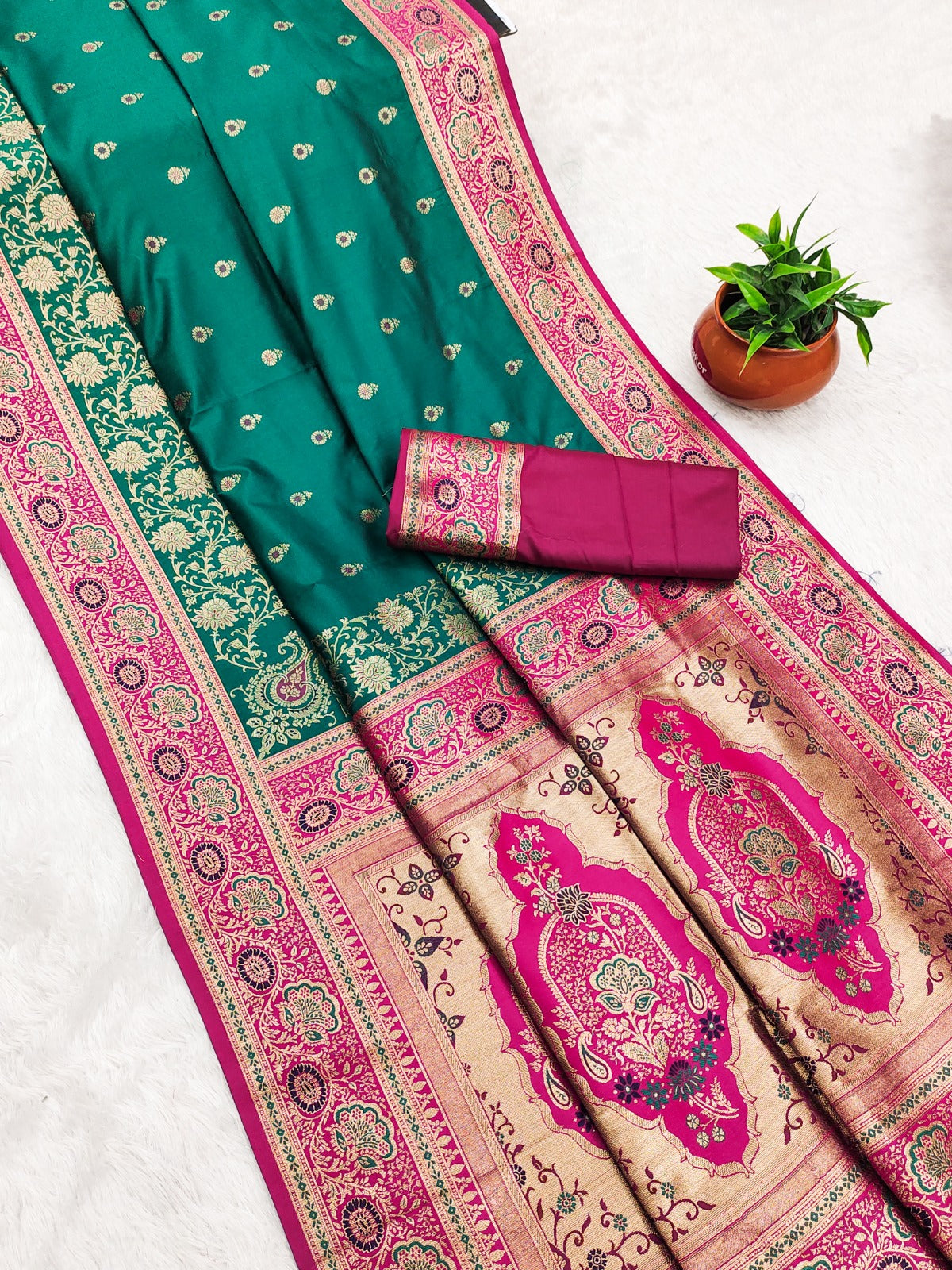 Green and pink saree with intricate patterns on a white background