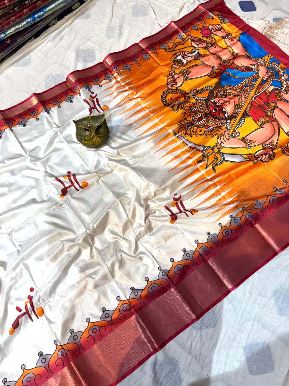 Decorative saree with intricate designs of Devi Durga on a white fabric background