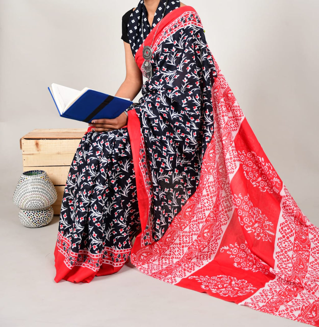 Person wearing a black floral dress with a red and white patterned dupatta, holding a book.