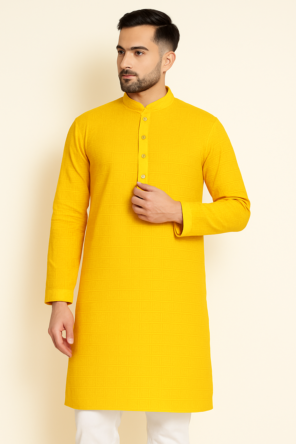 Man wearing a yellow kurta with white pants against a beige background
